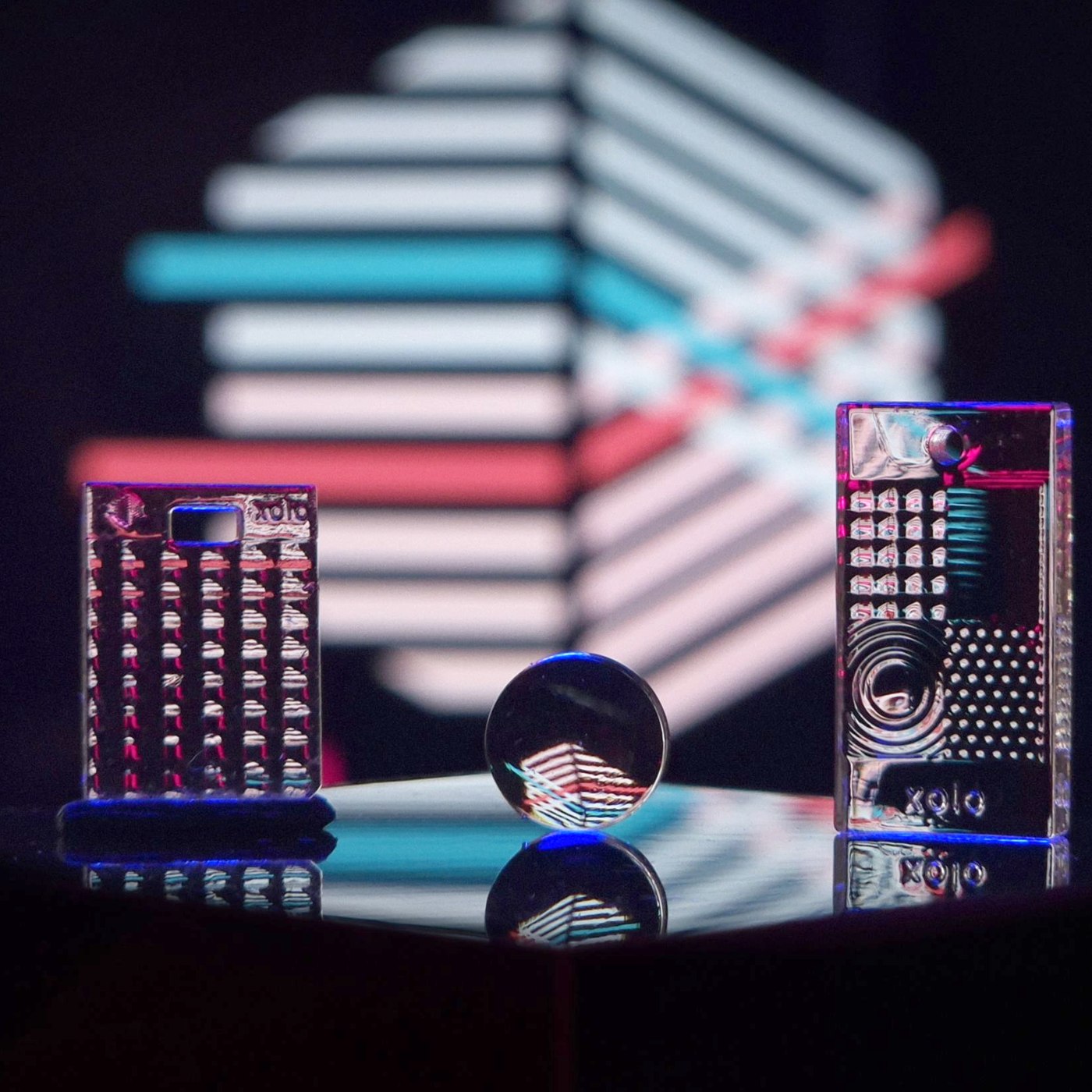 Two transparent test pieces and a small lens printed in xoloClear, with the xolo logo visible through them